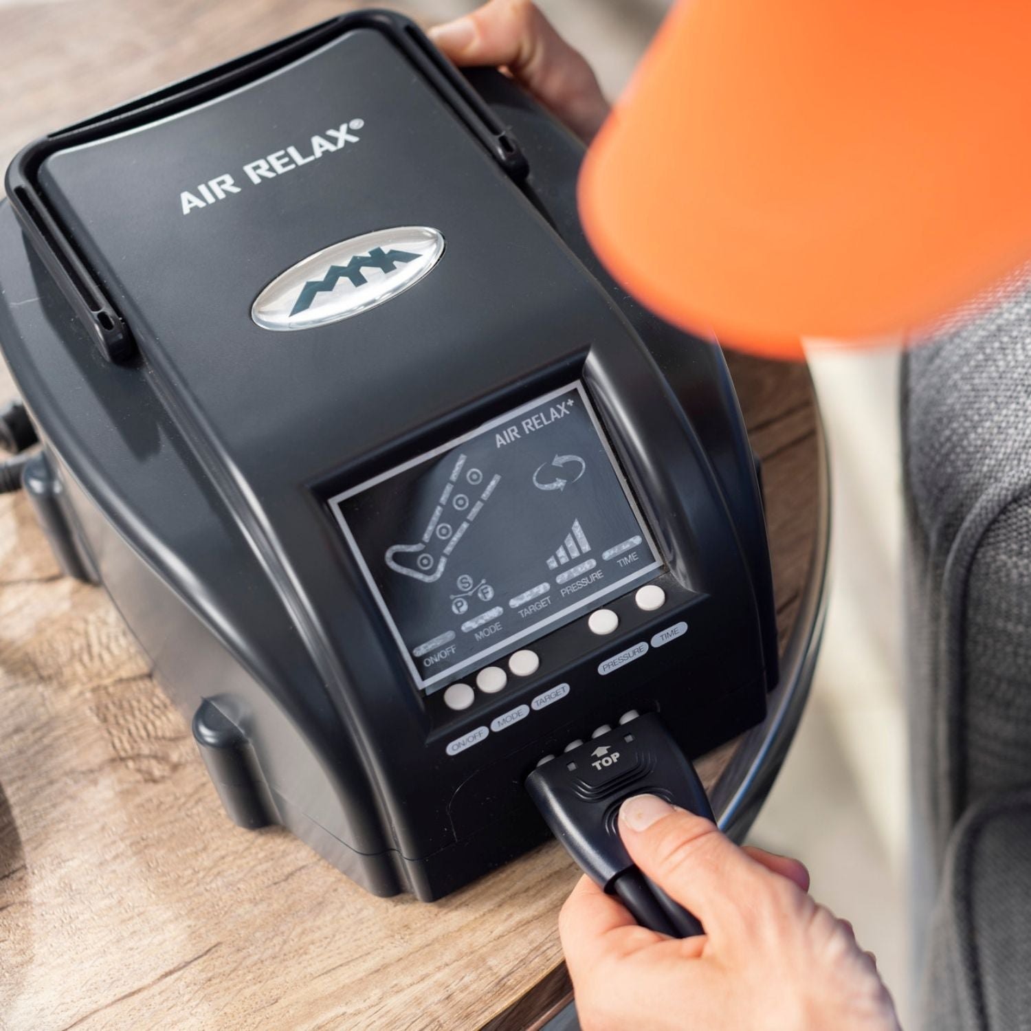 AIR RELAX PLUS AR-3.0 LEG RECOVERY SYSTEM — Person using the remote control for the pump device