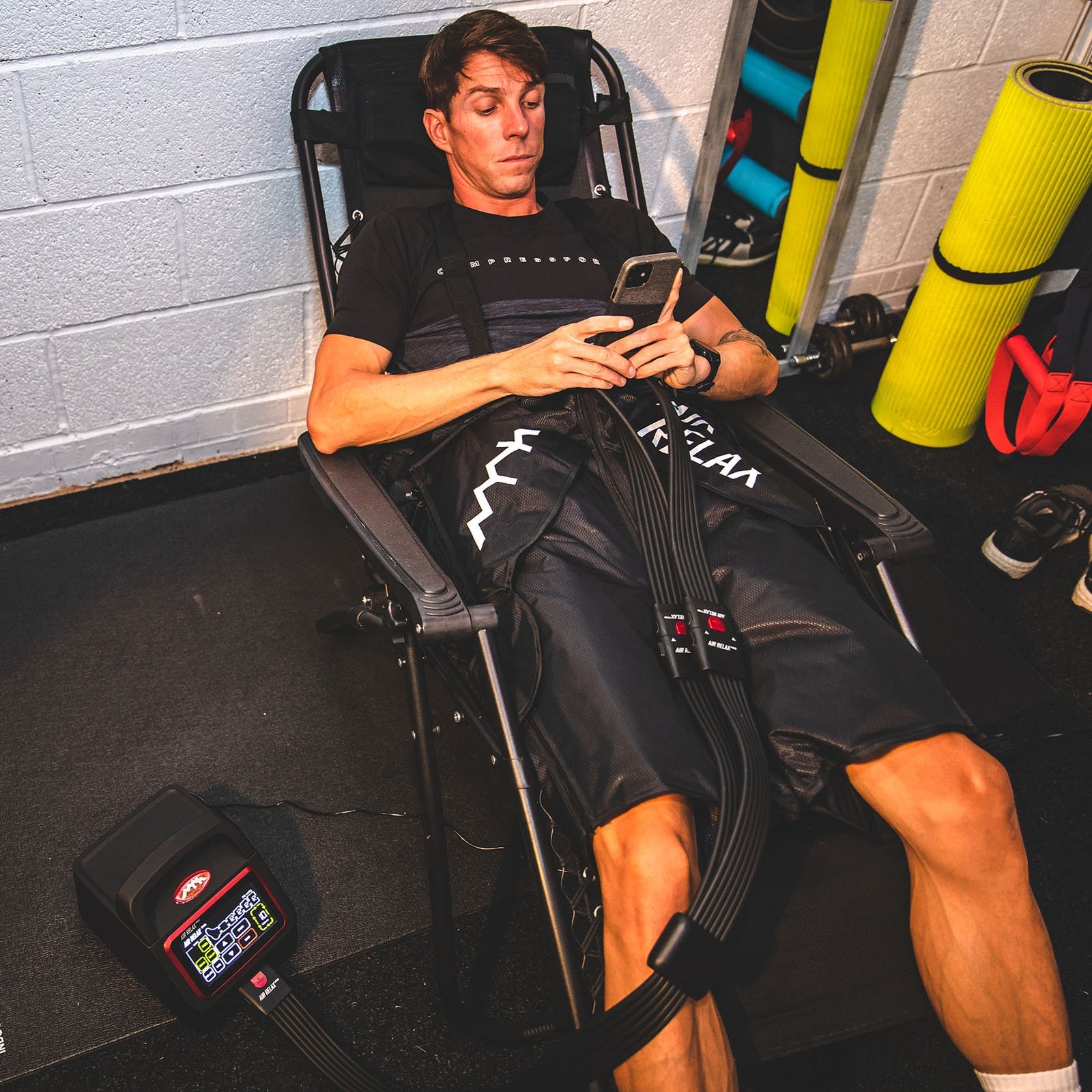 AIR RELAX PRO AR-4.0 SHORTS — Man wearing recovery shorts in a deckchair with hose visible